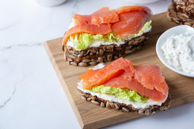 Creamy avocado and smoked salmon on toasted wholemeal bread with a lime wedge.