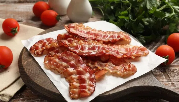Fresh strips of raw bacon and a block of butter on a kitchen counter ready for storage.